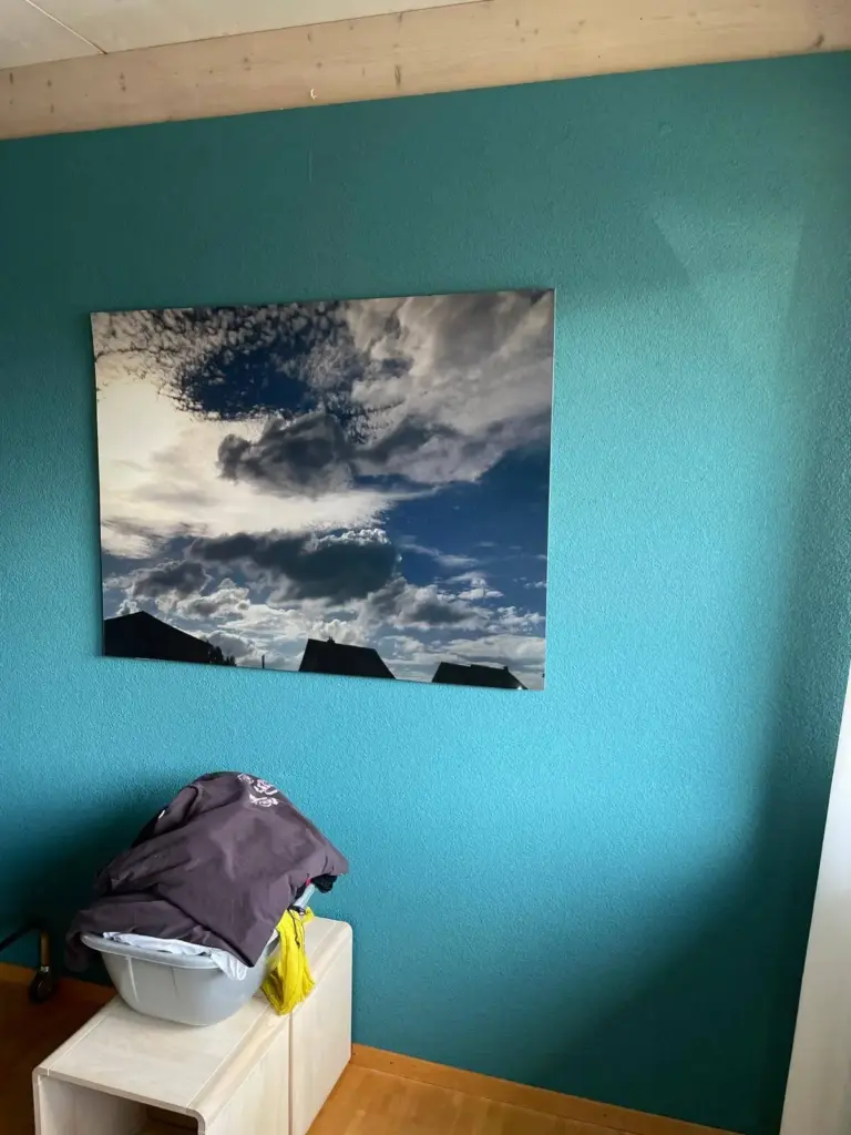 Zimmer mit petrolfarbener Akzentwand und grossem Wolkenbild
