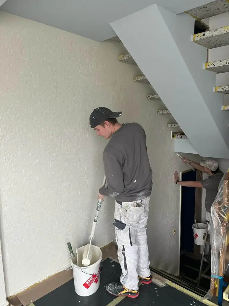Zwei Maler streichen Wand und Treppenaufgang