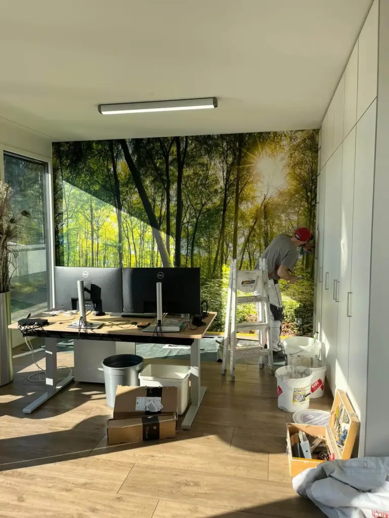 Büro mit grossformatiger Wald-Fototapete hinter dem Arbeitsplatz