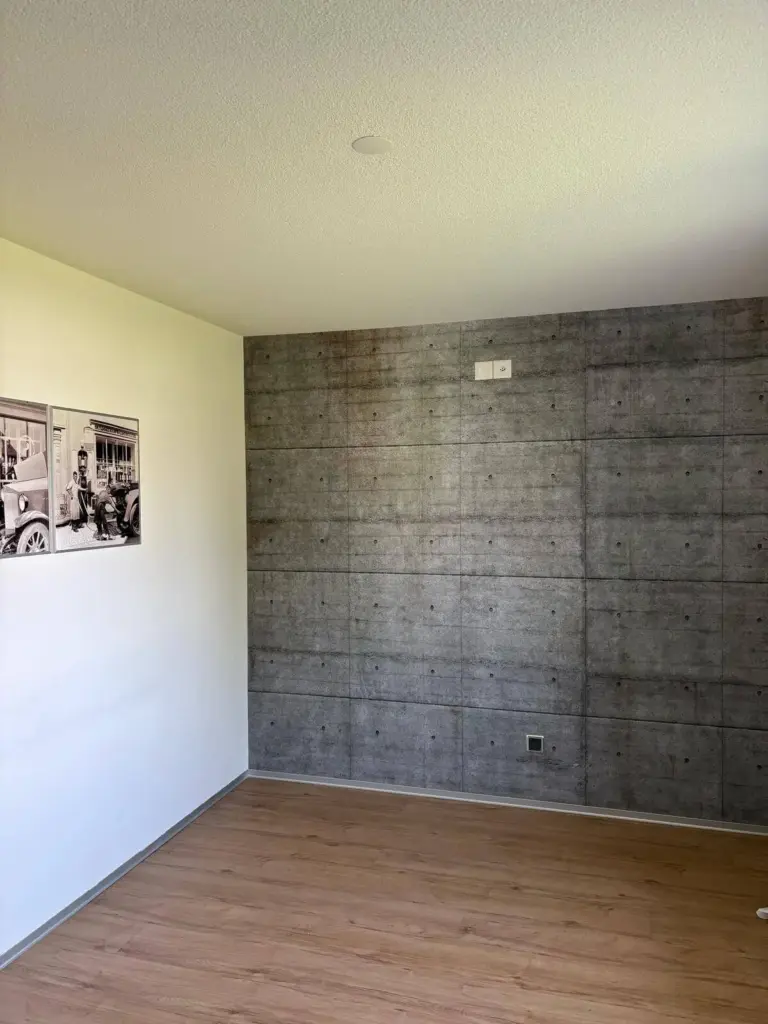 Zimmer mit Betonoptik-Tapete an der Stirnwand